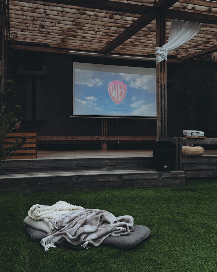 Outdoor cinema with comfy seating and a projector screen for a cozy movie night experience.