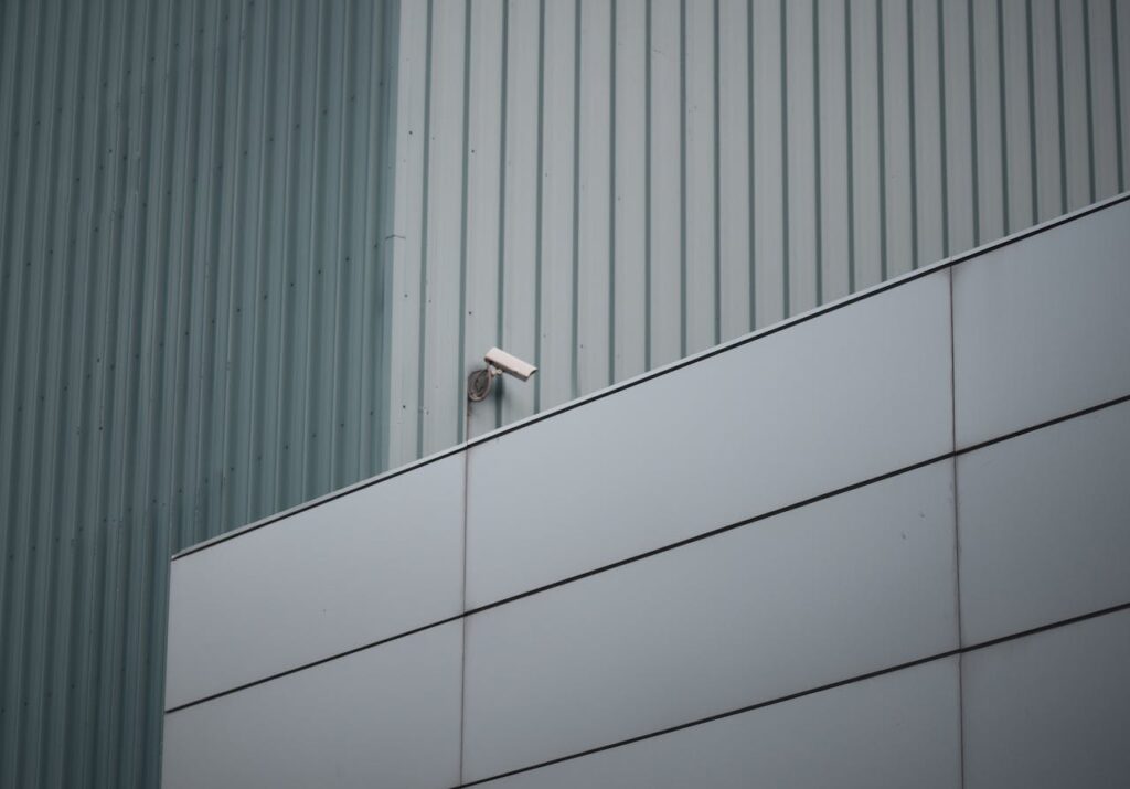 Security camera on modern building facade, highlighting urban safety and surveillance.
