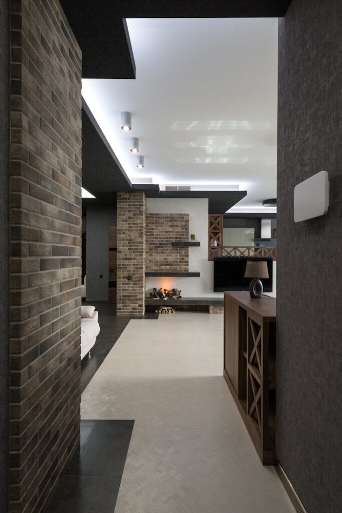 Corridor with brick wall leading to spacious living room with decorative elements with stylish design in modern apartment with glowing lamps
